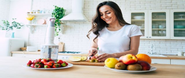 Anti-ageing diets: beautiful woman making healthy fruit smoothie