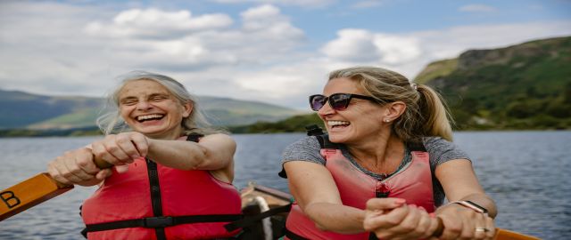 Two women rowing on a lake wearing red boyancy vests. They are staying healthy over 45 with exercise and nutrition.