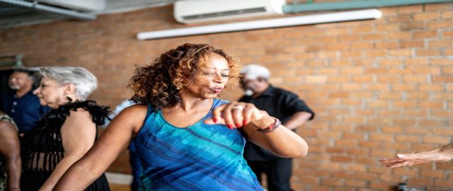 Mid-life women in a blue dress, at a dance class.