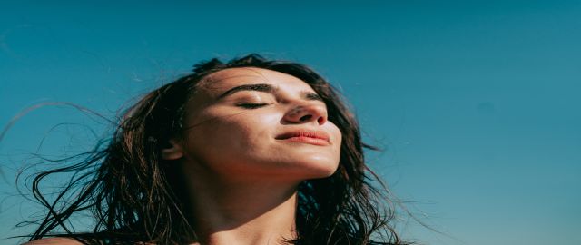 Headshot of pretty young woman against a blue sky. Clearing her brain fog.