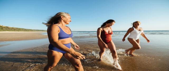 A group of three friends walking along the beach together.