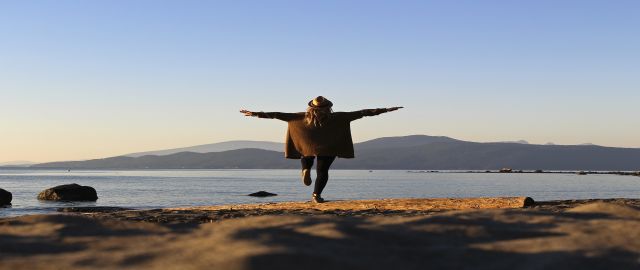 Young woman staying centred as she stands on one leg, arms spread wide.