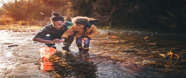 Getting enough vitamin d to support your immunity is important: father and son fishing with fishing net in river in the autumn sunlight.