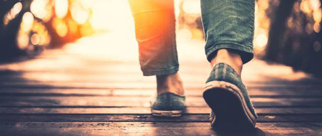 Close up of feet walking on a boardwalk at a summer sunset