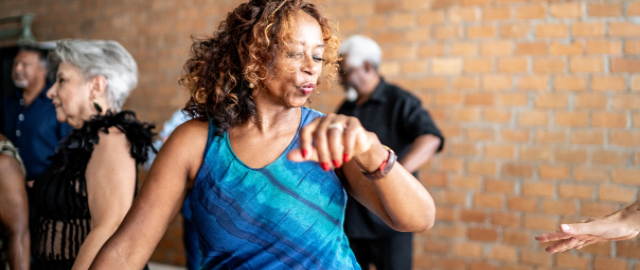 Mid-life women in a blue dress, at a dance class.
