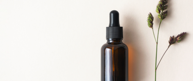Minimalist flatlay of a brown glass tincture bottle on a cream background.