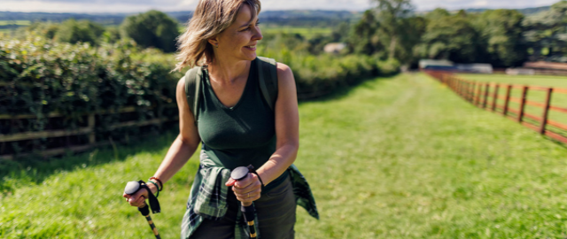 Midlife women hiking on a sunny day up a grassy hill