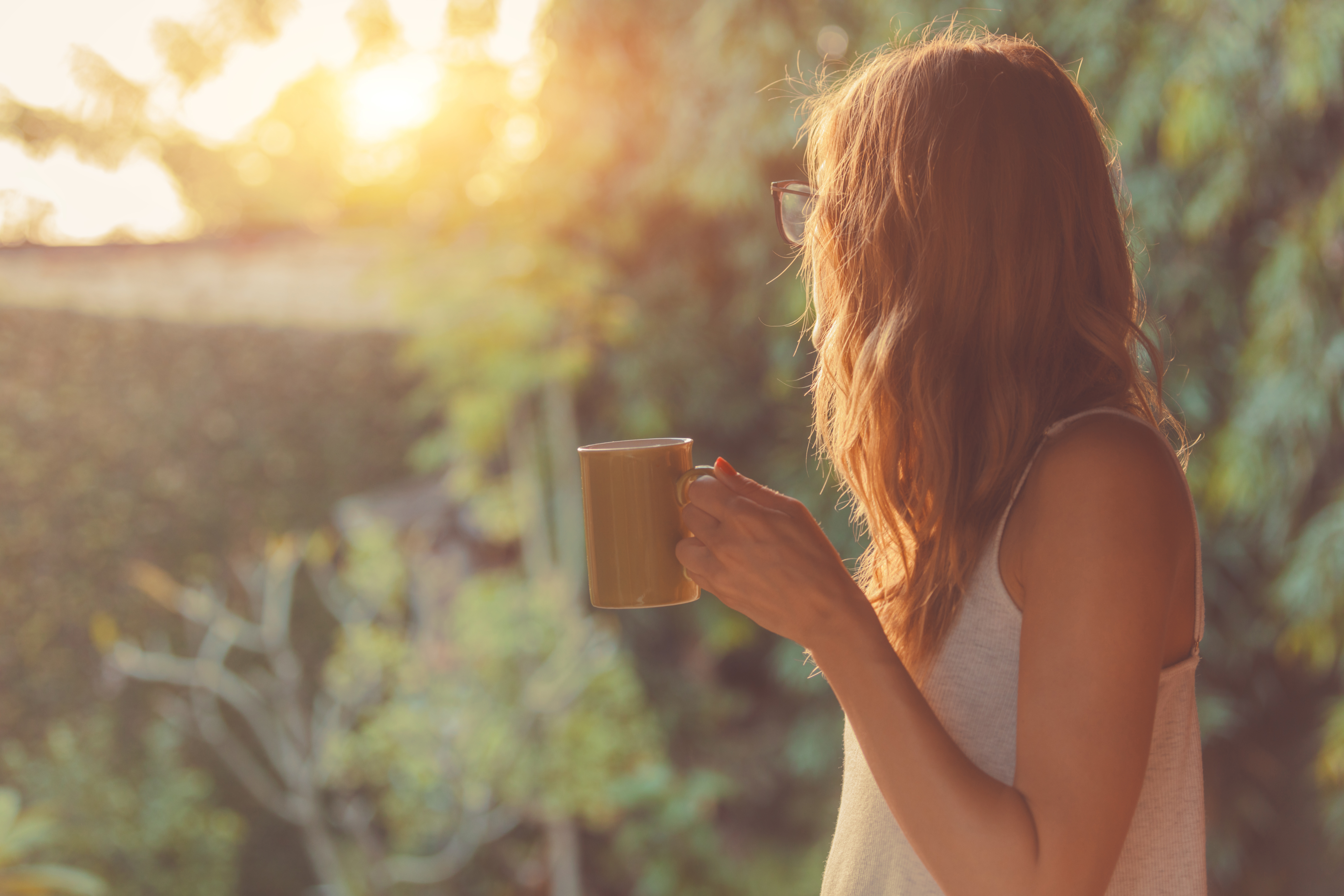 Cute girl working on her mindset enjoying morning coffee on the porch.