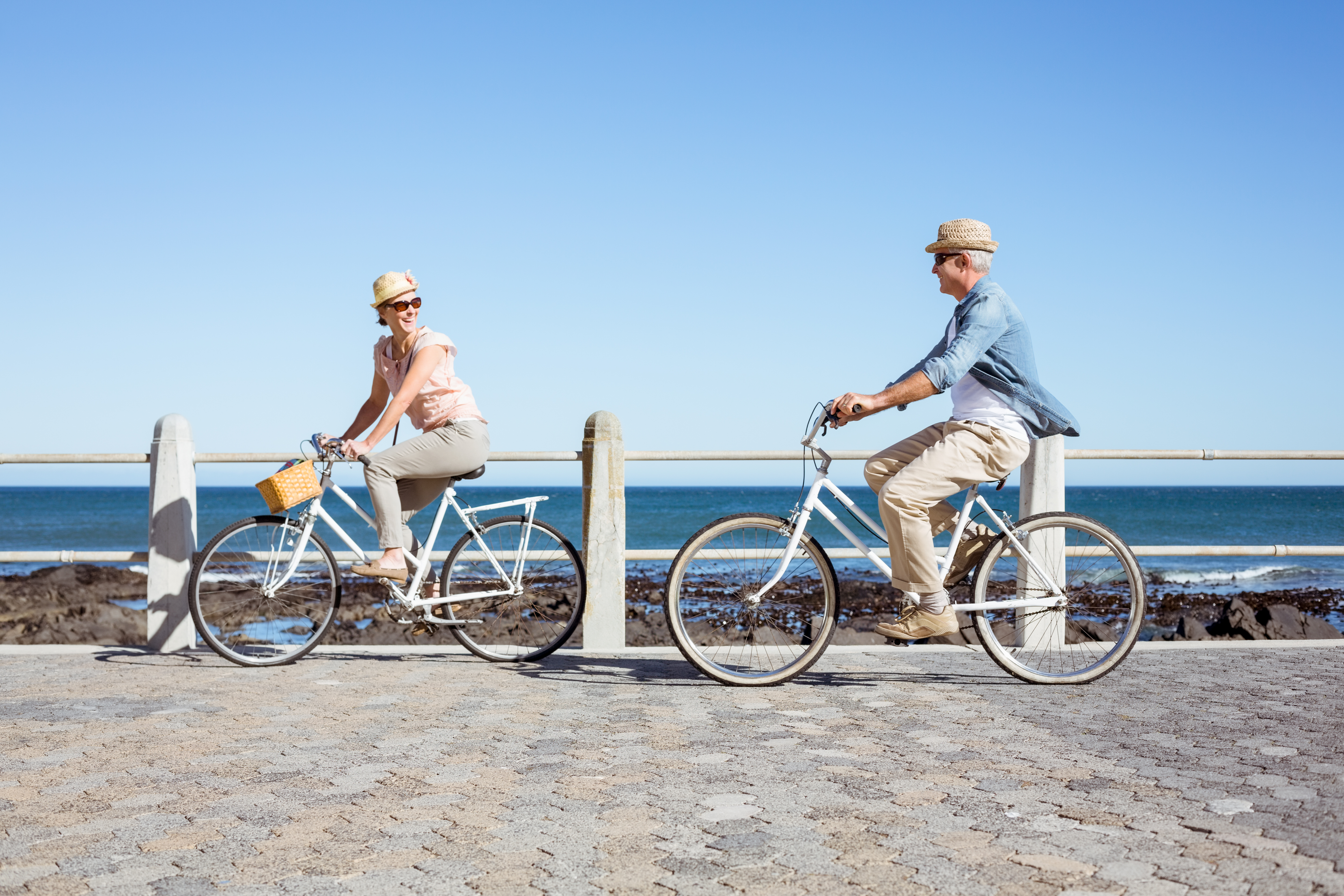 Happy casual couple moving well going for a bike ride on the pier