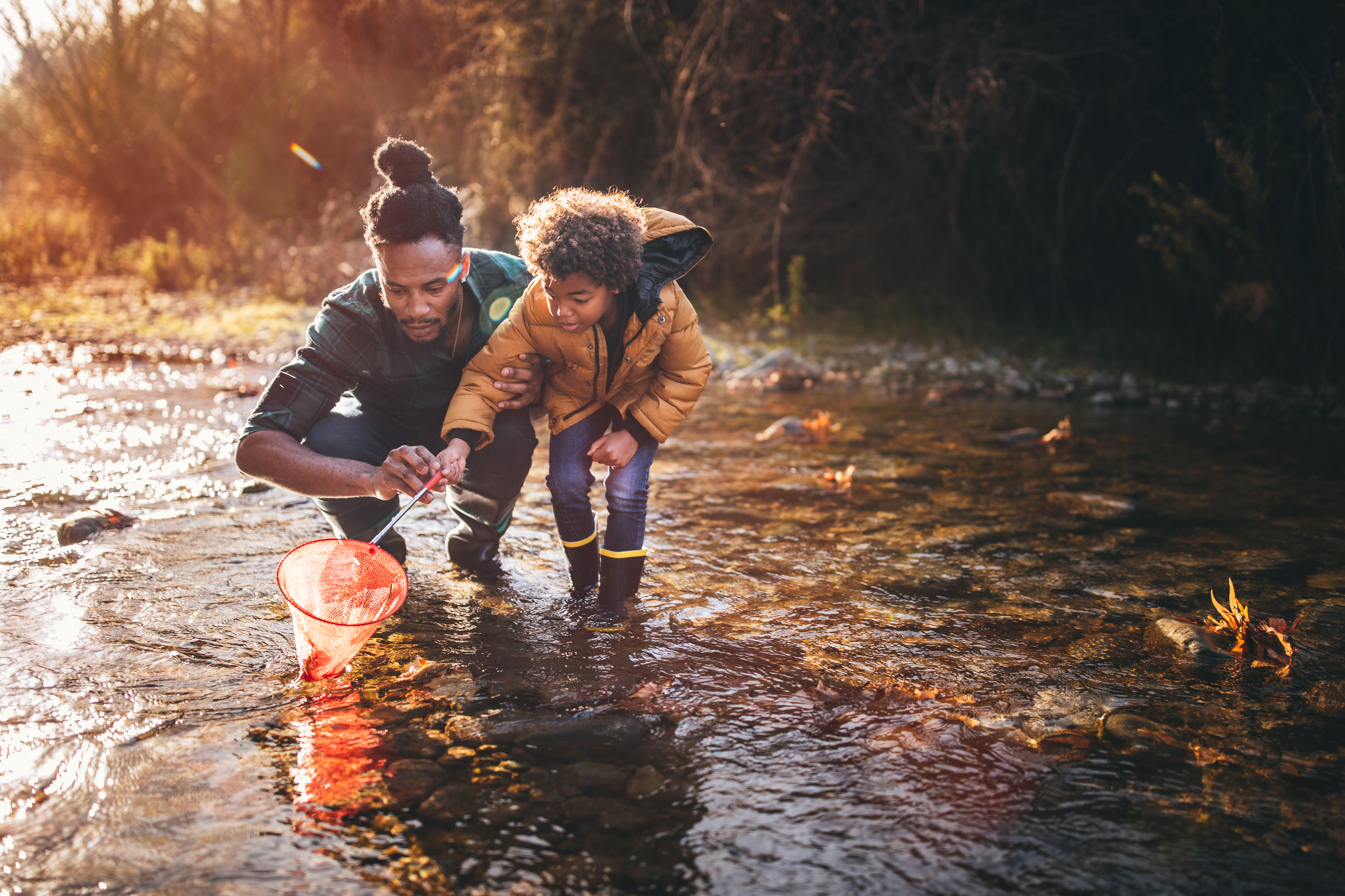 Getting enough vitamin d to support your immunity is important: father and son fishing with fishing net in river in the autumn sunlight.