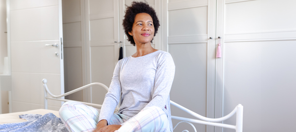 Menopause and insomnia: African mature women sat on the bed after a nights rest